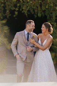 Newlyweds embracing under a vibrant Cabo sunset on the beach.